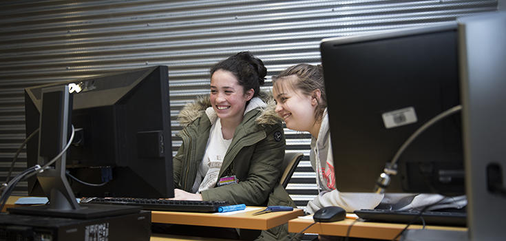 Deux adolescents travaillant derrière un ordinateur. 