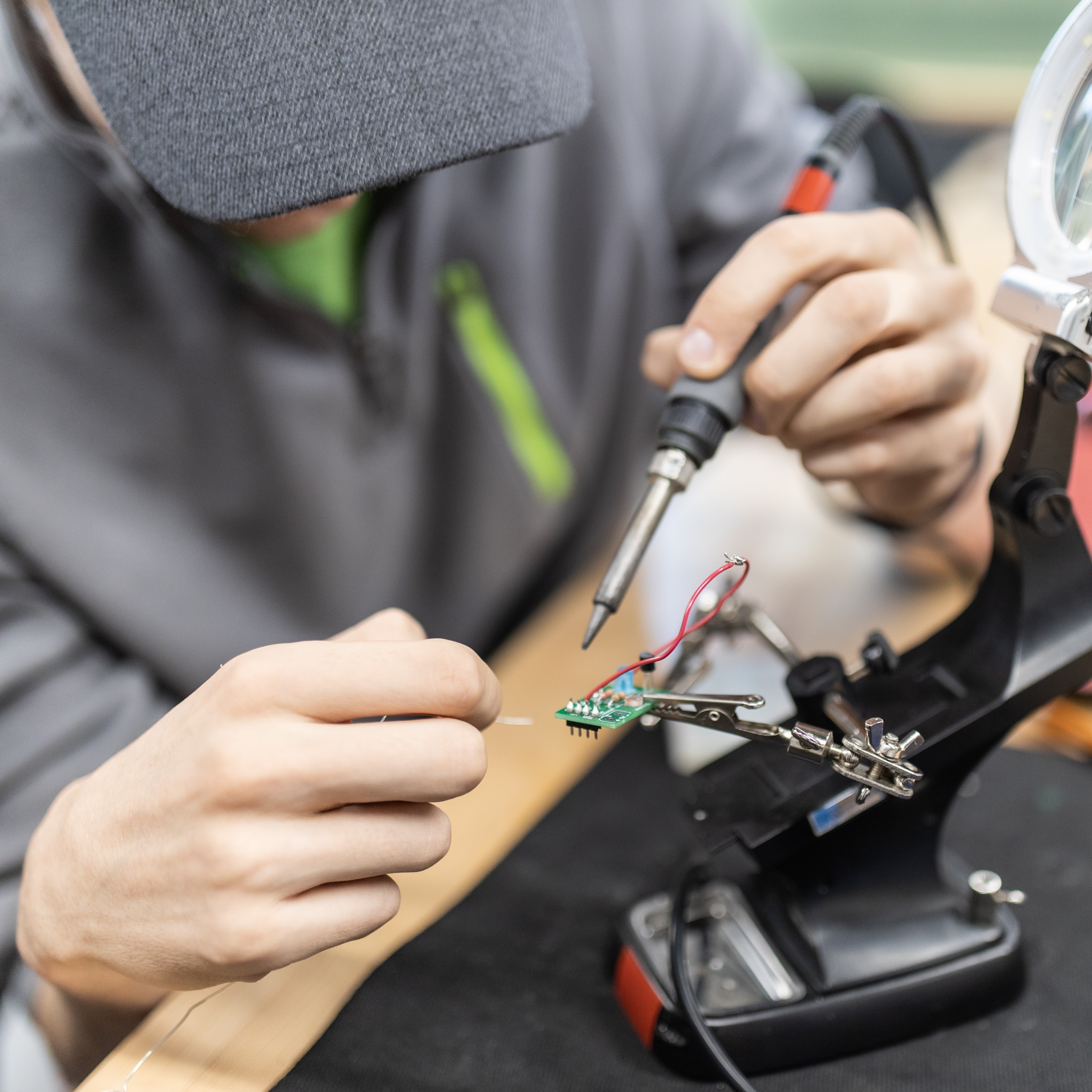 A student soldering a wire to a chip.
