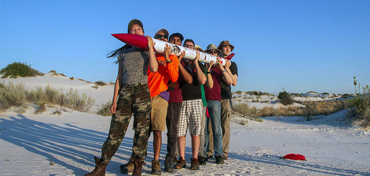 Team picture of people holding a rocket.