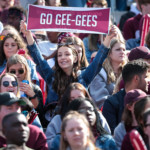 Woman in crowd holding a GO GEE GEES banner