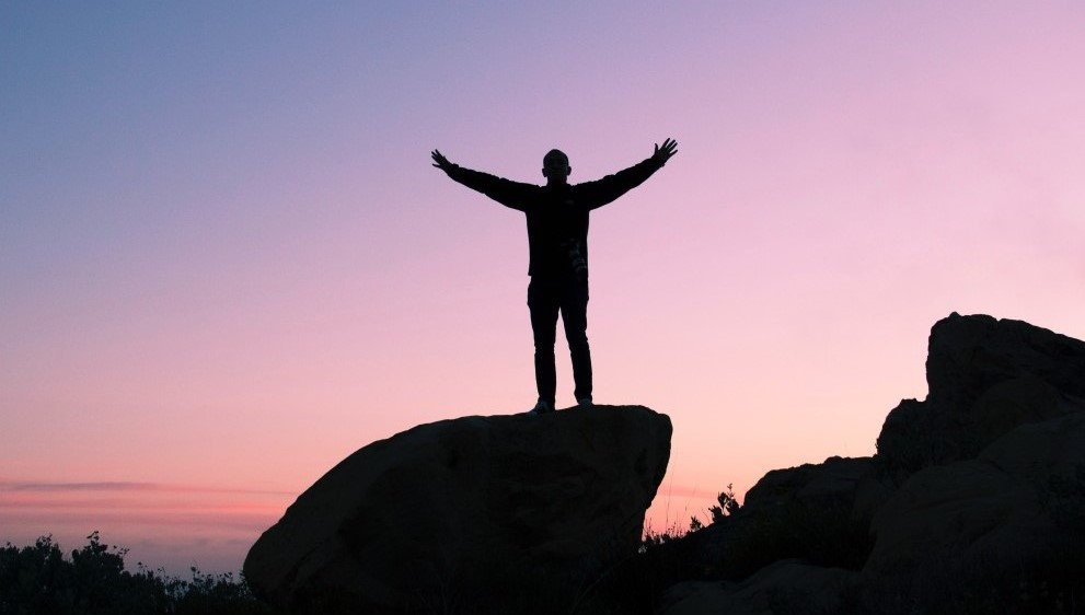 Person standing proud on top of a rock