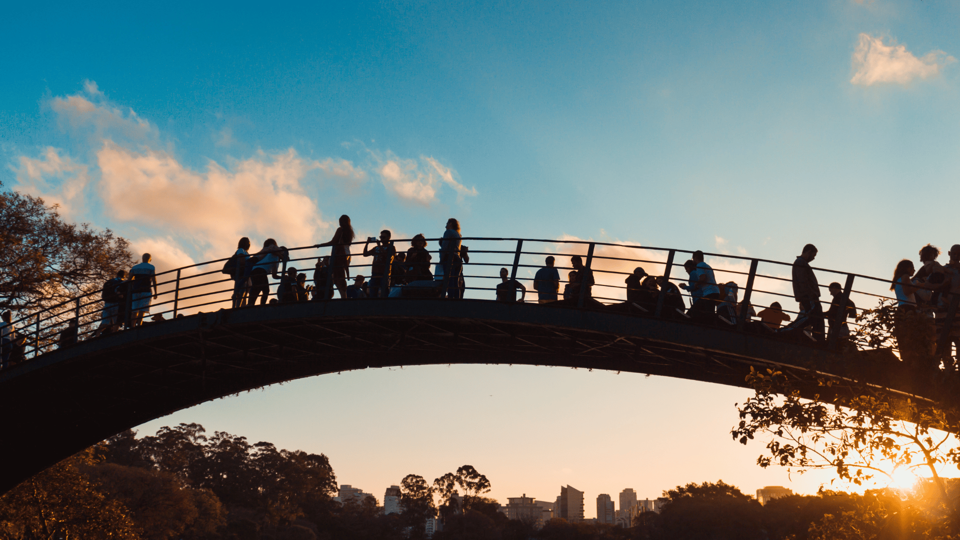 Silhouettes of people on bridge at sunset