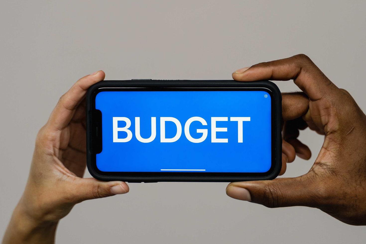 Hands holding a smart phone with "budget" written on it