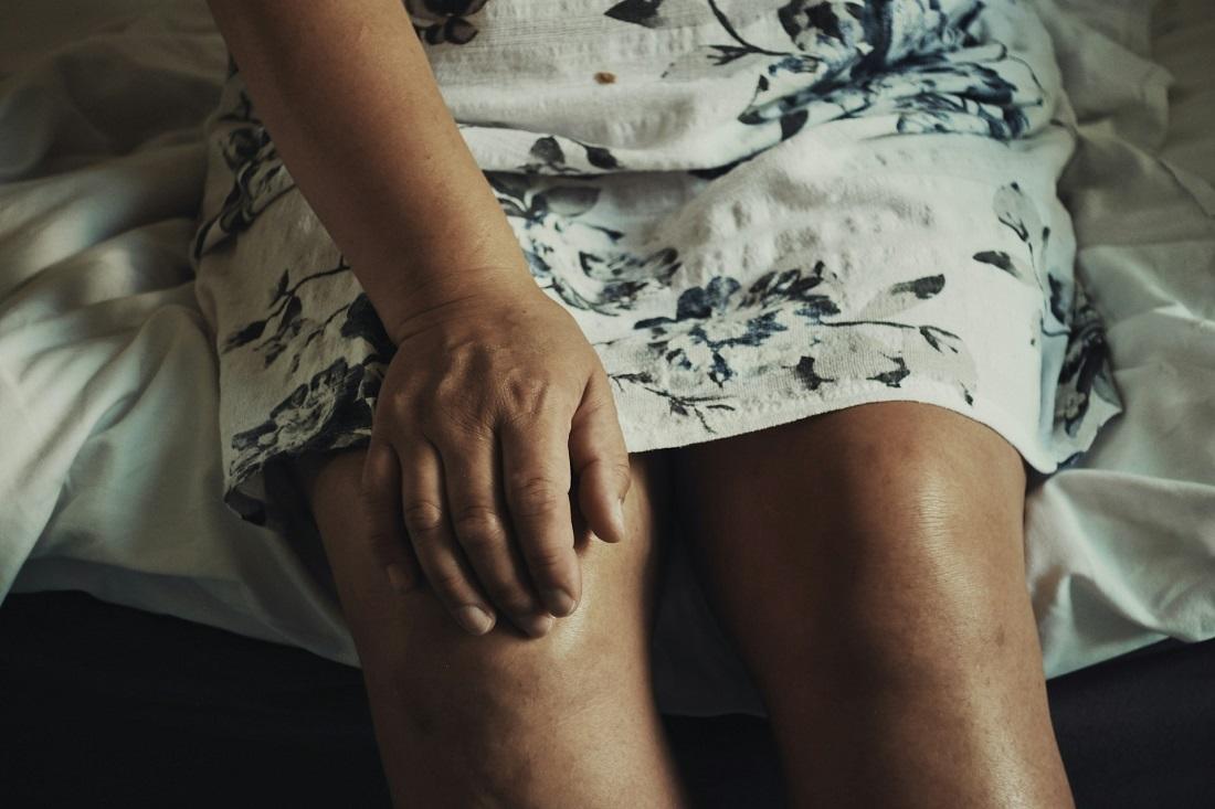Woman's hand clutching knee in likely pain