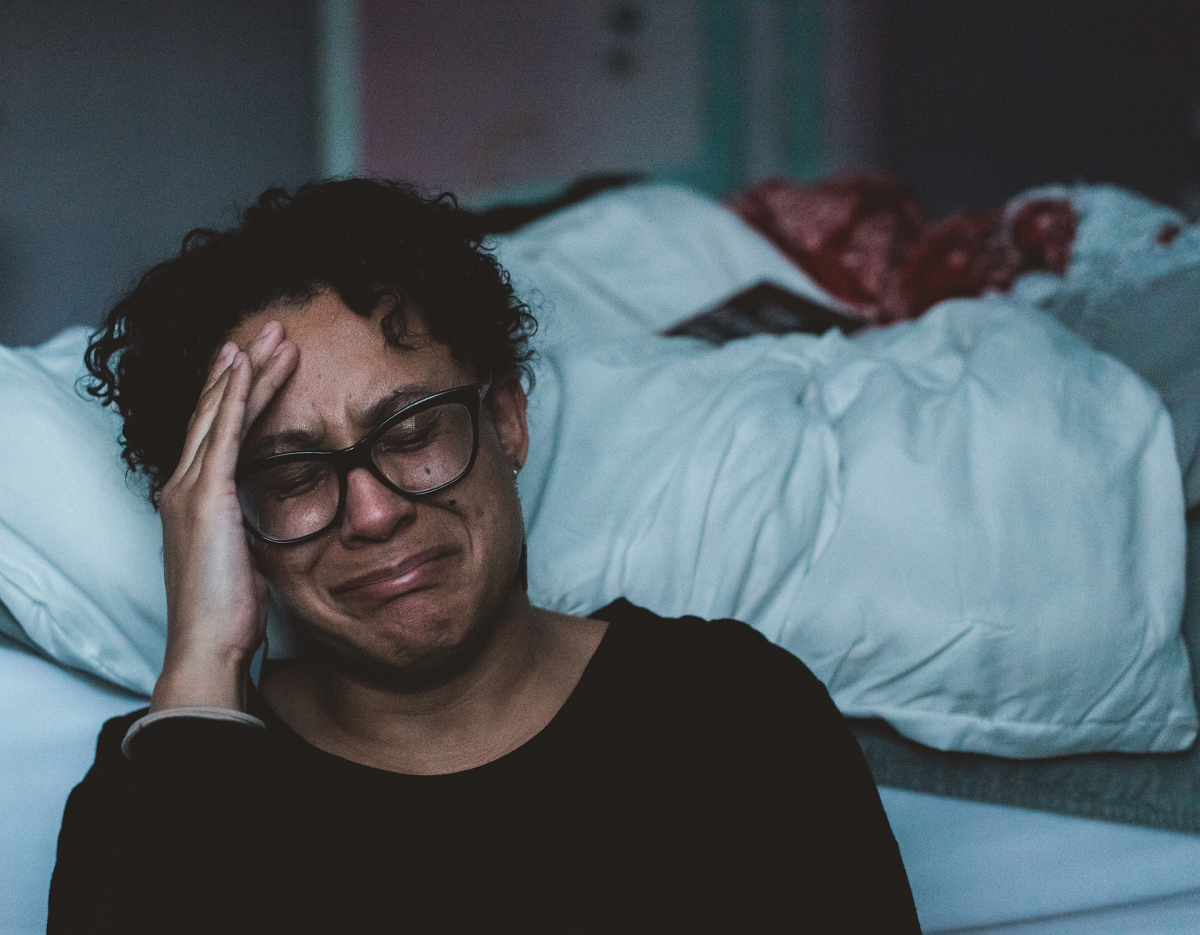 Femme noire d'âge moyen pleurant au pied du lit